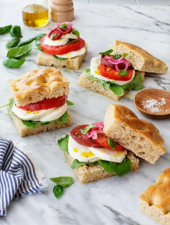High-Protein Tomato, Mozzarella & Sandwich 6 Open-faced tomato and mozzarella sandwiches on focaccia bread with basil, red onion, and olive oil.