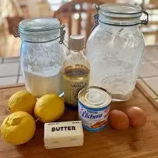 Easy baby lemon impossible pies with sweetened condensed milk 6 Ingredients on a wooden board for lemon impossible pies, including sweetened condensed milk, lemons, butter, eggs, flour, sugar, and vanilla extract.