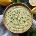 Fresh Lemon Herb Tahini Sauce 5 A vibrant close-up of Lemon Herb Tahini sauce made with fresh herbs, garlic, and lemon juice, styled with parsley and lemons for a bright, zesty flavor profile.